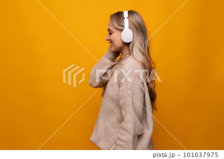 girl attentively listens to a podcast in headphones on a yellow background 101037975