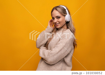 girl attentively listens to a podcast in headphones on a yellow background 101038052