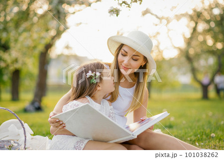 Caucasian family, mother and daughter together watching a family photo album in spring at a picnic in the garden, the concept of family values, generations and memories 101038262