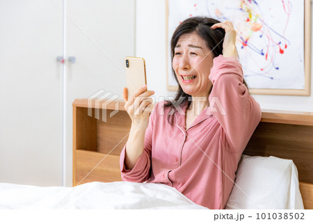 ベッドでスマホを見る女性 ベッドでスマホを見る女性 101038502