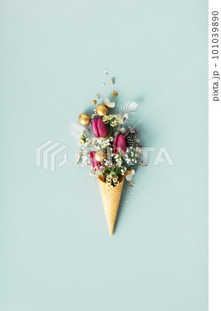 Ice cream cone with beautiful flowers and golden easter eggs on blue background flat lay 101039890