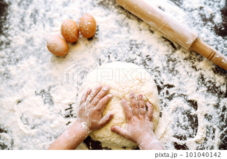 Small hands kneading dough. Little child preparing dough for backing. Kid's hands, some flour. Small hands kneading dough. Little child preparing dough for backing. Kid's hands, some flour. 101040142