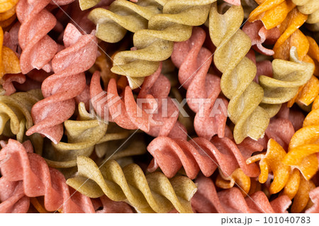 Rice vegetable pasta in the form of spirals, top view. Healthy rice pasta with tomatoes, selenera, carrots and beets 101040783