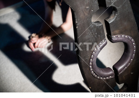 Female hands in wooden shackles during role-playing games. Shameful pillar and leather cuffs for sex. BDSM Domination and punishment. Female hands in wooden shackles during role-playing games. Shameful pillar and leather cuffs for sex. BDSM Domination and punishment. 101041431