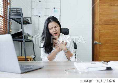 Portrait of young Asian female representative showing acute chest pain from sitting for a long time at work. High quality photo 101041876