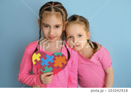 The girl gently laid her head on the shoulder of the older sister holding the autism symbol. The girl gently laid her head on the shoulder of the older sister holding the autism symbol. 101042918
