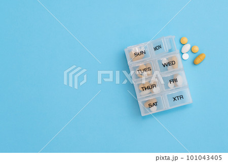 Top view of pill organizer with variety of pills and supplement. Weekly Pill container on blue background with copy space 101043405