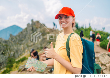 Young woman traveler with a backpack and a map Girl tourist in mountain read the map.Travel and wanderlust concept. Amazing chill moment. Young woman traveler with a backpack and a map Girl tourist in mountain read the map.Travel and wanderlust concept. Amazing chill moment. 101043412
