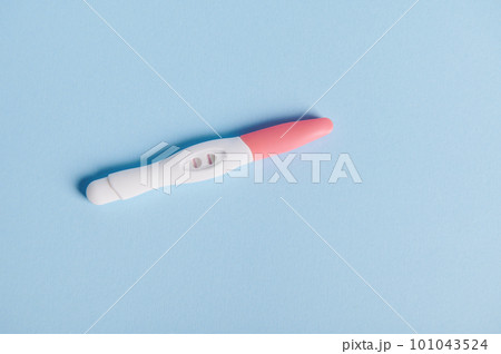 View from above of a positive pregnancy test over blue background with free advertising space for text. Women's health and fertility concept. Rapid diagnosis of pregnancy at home. Gynecology. Medicine 101043524
