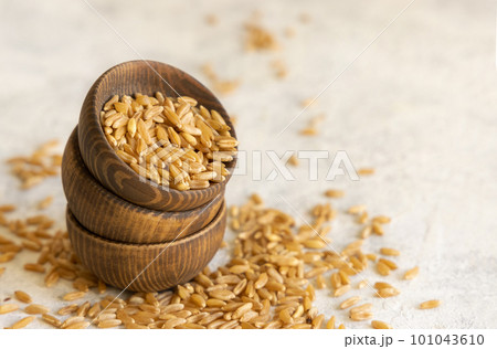 Wooden bowls of raw dry rye grain on white table close up 101043610