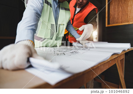 Architect and Engineer working with blueprints for architectural plan, engineer sketching a construction project, green energy concept 101046892