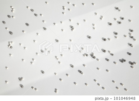 Many little white and gray balls scattered on a white background in the bright light, dropping shadows. Geometrical abstract futuristic wallpaper with lots of small round particles Many little white and gray balls scattered on a white background in the bright light, dropping shadows. Geometrical abstract futuristic wallpaper with lots of small round particles 101046948