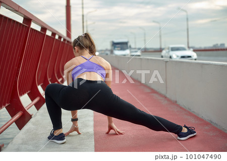 Girl athlete stretching in the morning outside, in the city, on modern bridge crossing river. Active healthy lifestyle. Sport and recreation concept. Girl athlete stretching in the morning outside, in the city, on modern bridge crossing river. Active healthy lifestyle. Sport and recreation concept. 101047490