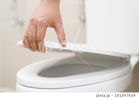 close up hand of a woman closing the lid of a toilet seat. Hygiene and health care concept. close up hand of a woman closing the lid of a toilet seat. Hygiene and health care concept. 101047634