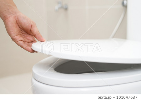 close up hand of a woman closing the lid of a toilet seat. Hygiene and health care concept. close up hand of a woman closing the lid of a toilet seat. Hygiene and health care concept. 101047637