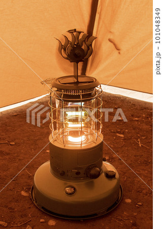 冬のキャンプ場のテントの中で石油ストーブとストーブファンで暖を取る 101048349