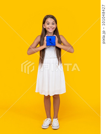 positive teen girl hold present box on yellow background positive teen girl hold present box on yellow background 101048427