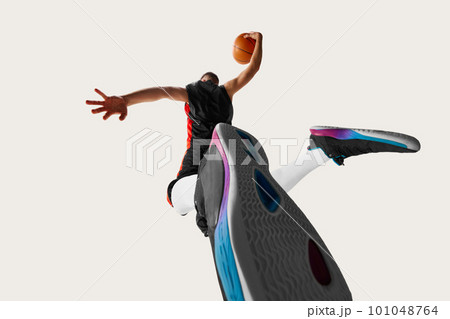 A fisheye view of male professional basketball player jumping and throwing ball into the basket over white background 101048764