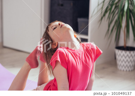 Child performs the exercise gymnastics at home on a mat 101049137