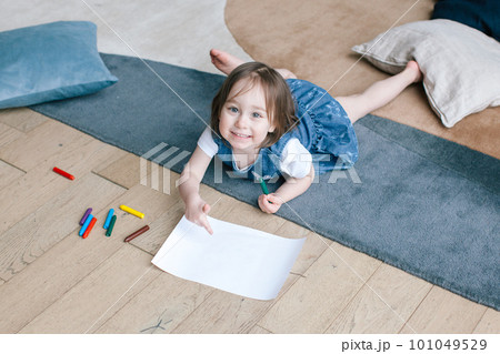 A two-year-old girl lies on the floor and draws with pencils. A two-year-old girl lies on the floor and draws with pencils. 101049529