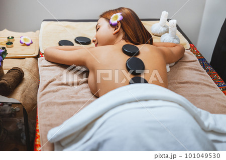 beautiful woman receiving hot stone massage in spa 101049530