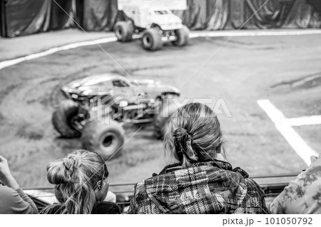 Selective focus on spectators in the stands with hearing protection watching a monster truck rally. Selective focus on spectators in the stands with hearing protection watching a monster truck rally. 101050792