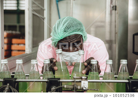 African Nigerian staff worker work in drink factory quality check at conveyor belt product line African Nigerian staff worker work in drink factory quality check at conveyor belt product line 101052536
