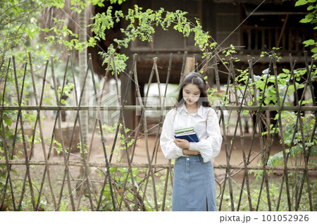 Pretty girl holding some books near a fence Pretty girl holding some books near a fence 101052926