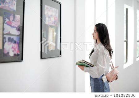 Female student holding some books and looking at an information board Female student holding some books and looking at an information board 101052936