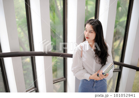Young Asian woman standing near the glass door Young Asian woman standing near the glass door 101052941