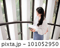 Young woman holding some notebooks near the glass door 101052950