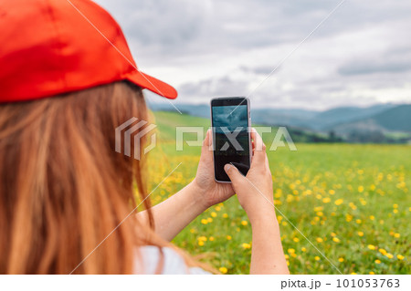 Tourist taking picture on her smartphone from top of mountain. Caucasian woman in hat and with backpack on rock. Travel concept. Tourist taking picture on her smartphone from top of mountain. Caucasian woman in hat and with backpack on rock. Travel concept. 101053763