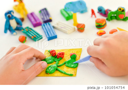 A close-up of hands with plasticine, children's crafts and an application on the theme of harvest. A close-up of hands with plasticine, children's crafts and an application on the theme of harvest. 101054754