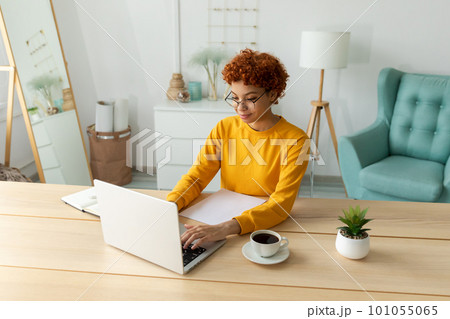 African american girl using laptop at home office looking at screen typing chatting reading writing email. Young woman having virtual meeting online chat video call conference. Work learning from home African american girl using laptop at home office looking at screen typing chatting reading writing email. Young woman having virtual meeting online chat video call conference. Work learning from home 101055065