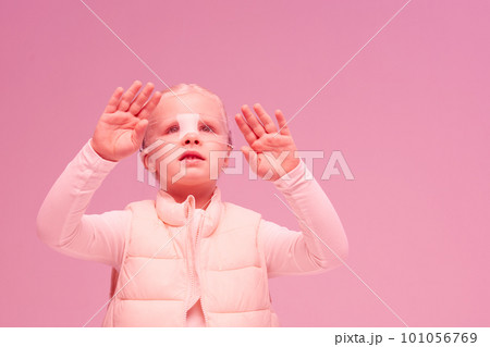 Girl in futuristic clothes and vr glasses is experiencing cyberspace with pink neon light on pink background, metaverse artificial intelligence, cyber space 101056769