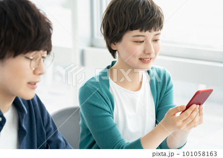 スマホを使う若い男女 101058163
