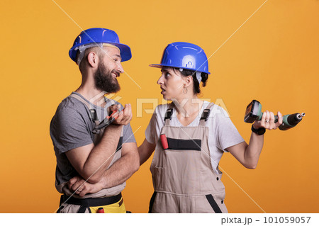 Engineering partners talking about different ideas for construction project, doing teamwork on renovation. Team of renovators working together using drill gun and pair of pliers in studio. Engineering partners talking about different ideas for construction project, doing teamwork on renovation. Team of renovators working together using drill gun and pair of pliers in studio. 101059057