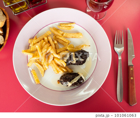 main course is fried fatty blood sausage with bow and slices of french fries complemented by bread main course is fried fatty blood sausage with bow and slices of french fries complemented by bread 101061063