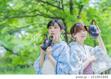 夏祭りのお面を手に浴衣でポーズをとる若い女性 101065866