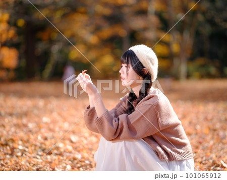 秋の公園で紅葉を拾う若い女性のポートレート 101065912