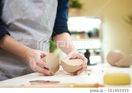 Female hands holding sliced clay ball for making ceramic goods in art pottery workshop Female hands holding sliced clay ball for making ceramic goods in art pottery workshop 101065959
