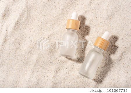Glass bottles with a cosmetic product on a natural sandy background. Top view. 101067755
