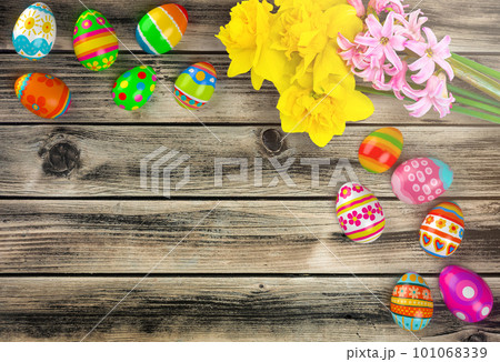 Colorful Easter eggs with yellow flowers on wooden background, flat lay. Space for text 101068339