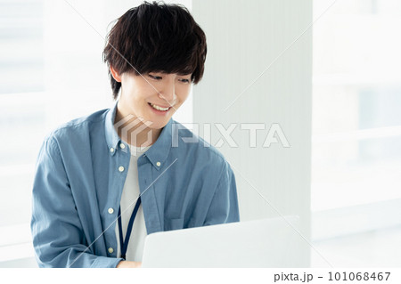 窓際でパソコンを操作する男性 101068467