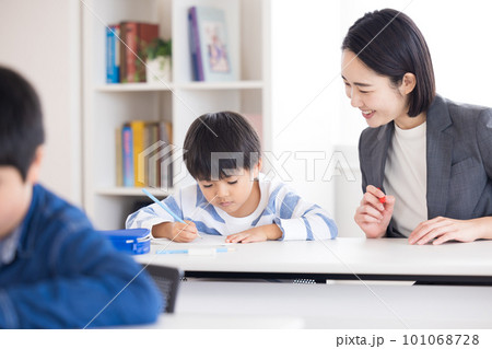 塾で勉強する小学生と先生 101068728