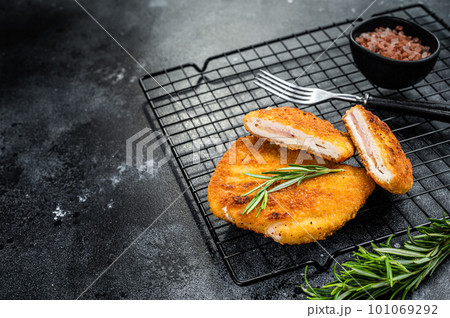 Schnitzel Cordon bleu fillet cutlet with ham and cheese. Black background. Top view. Copy space Schnitzel Cordon bleu fillet cutlet with ham and cheese. Black background. Top view. Copy space 101069292
