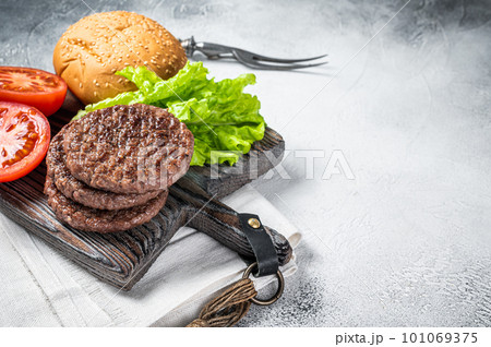 Fried cutlet for burger with vegetables and spices on wooden board. White background. Top view. Copy space 101069375