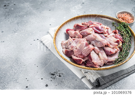 Raw chicken stomachs offals in a plate with herbs. Gray background. Top view. Copy space Raw chicken stomachs offals in a plate with herbs. Gray background. Top view. Copy space 101069376