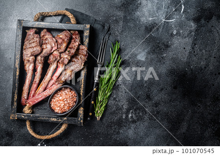 Grilled lamb chop steak, mutton meat cutlet in wooden tray. Black background. Top view. Copy space Grilled lamb chop steak, mutton meat cutlet in wooden tray. Black background. Top view. Copy space 101070545