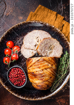 Baked delicious beef meatloaf, sliced meat loaf with bacon and herbs on a plate. Dark background. Top view Baked delicious beef meatloaf, sliced meat loaf with bacon and herbs on a plate. Dark background. Top view 101070727